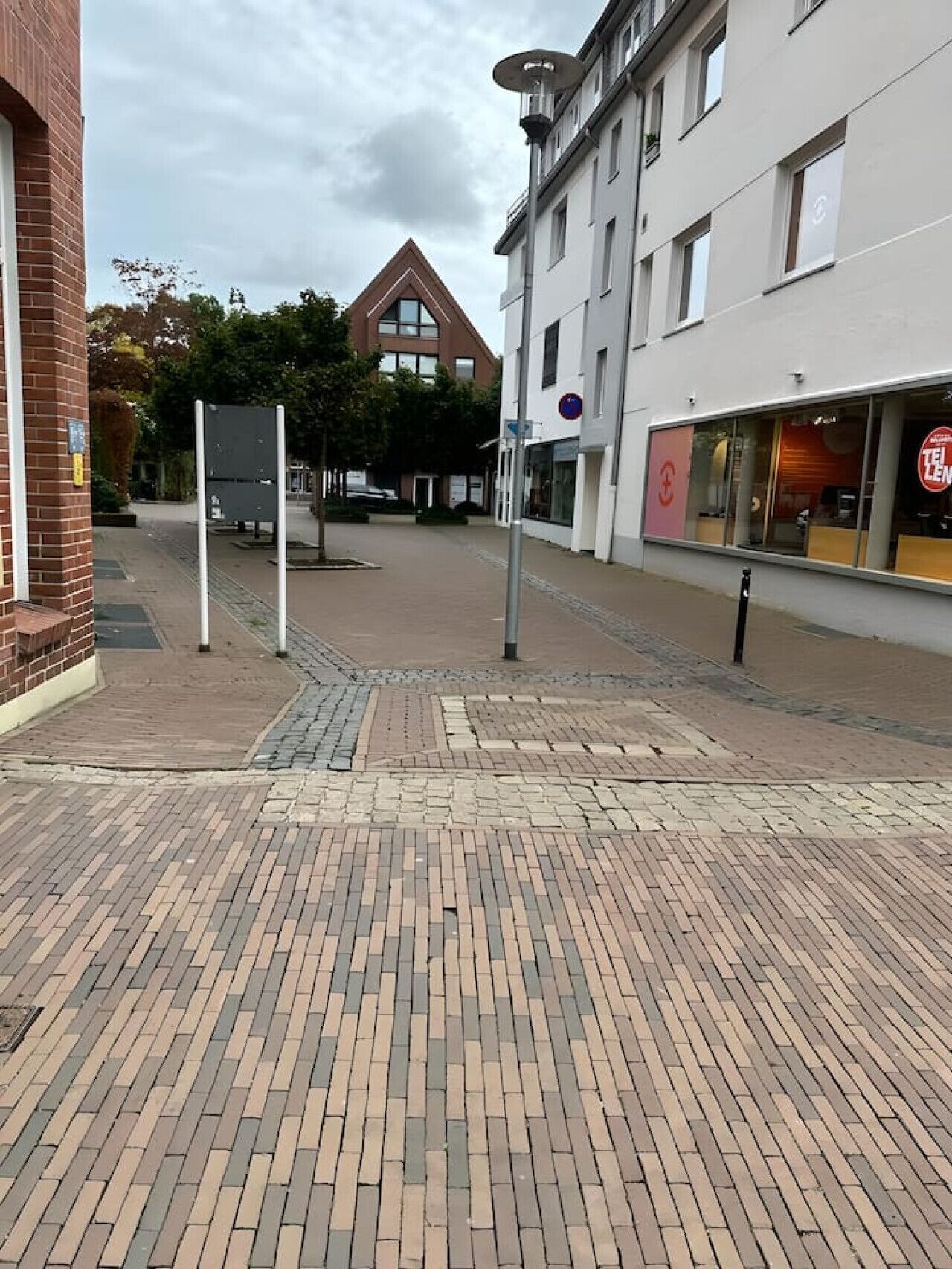 Een verhard voetpad met een baksteenpatroon, een gebouw met een bord en een restaurant met een herkenbaar logo.