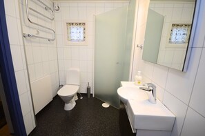 A small bathroom with a toilet, a sink, a mirror, and a window with a curtain.
