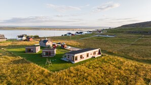 A coastal village with small houses, a road, and a body of water in the background. - Ekker Island Arctic Lodge (Vadsø)