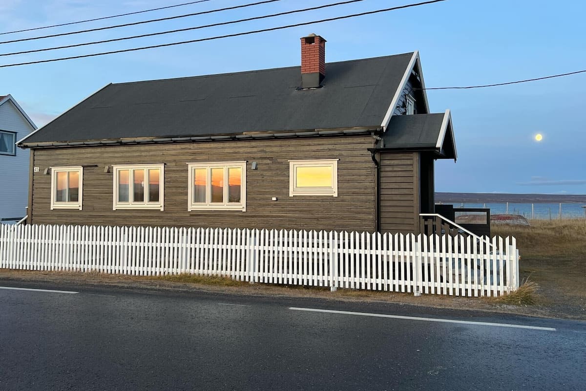 A two-story house with a dark brown exterior, a white picket fence, and a visible number '45' on the side.