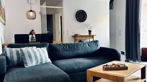 Un moderno salón con un sofá gris oscuro, una mesa de centro de madera y un reloj de pared.
