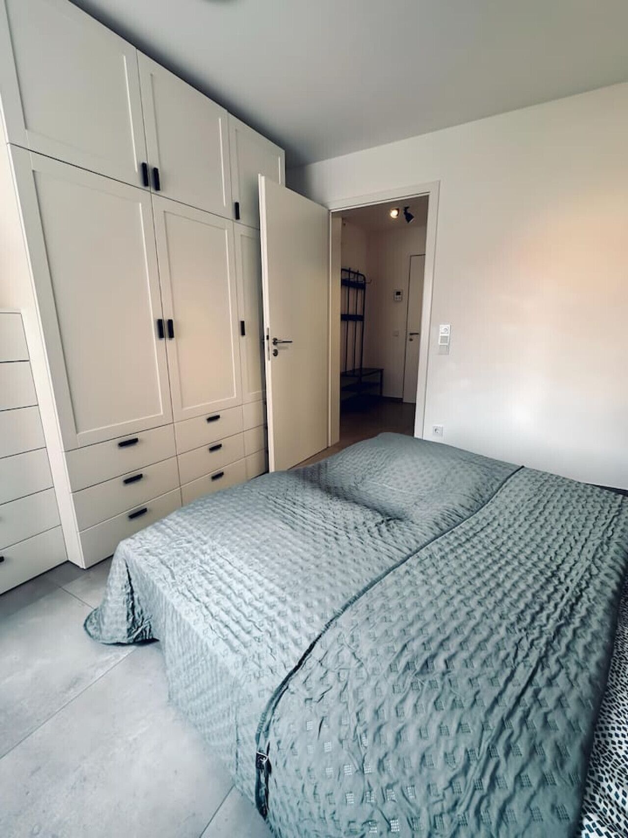 Un dormitorio con cama, armario y puerta que da a un baño.