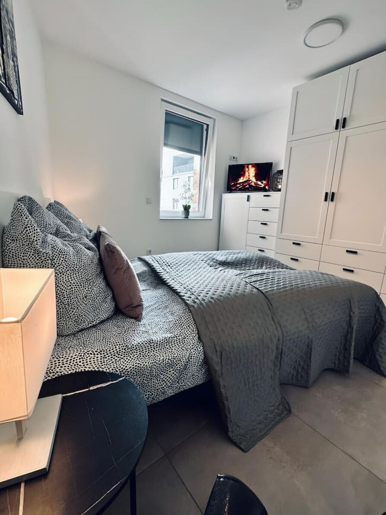 Un dormitorio con cama, televisión, ventana y armario.