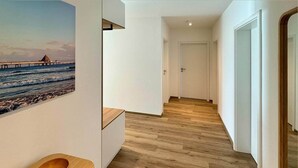 Ein Korridor mit Holzboden, einer weißen Tür und einem Gemälde eines Piers.