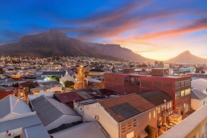 A cityscape with a prominent mountain in the background, a variety of buildings, and a church with a bell tower. - The Hub 602 (Cape Town)
