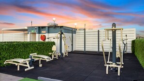 Outdoor exercise equipment, a covered area, and a building with a sign. - The Hub 602 (Cape Town)