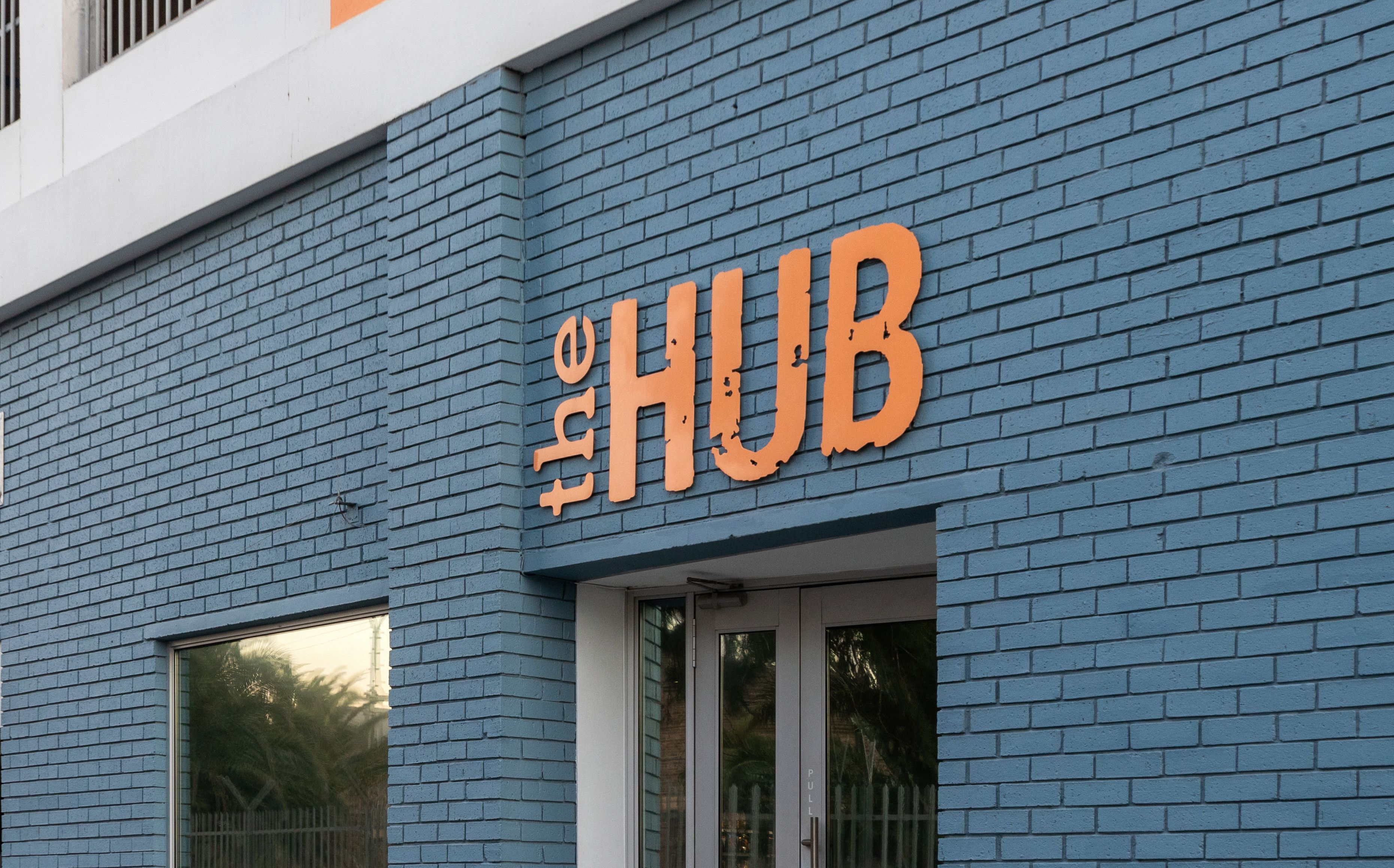 A building with a blue brick facade and a large orange sign that reads "HUB".
