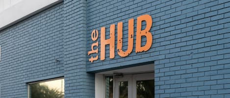 A building with a blue brick facade and a large orange sign that reads "HUB".