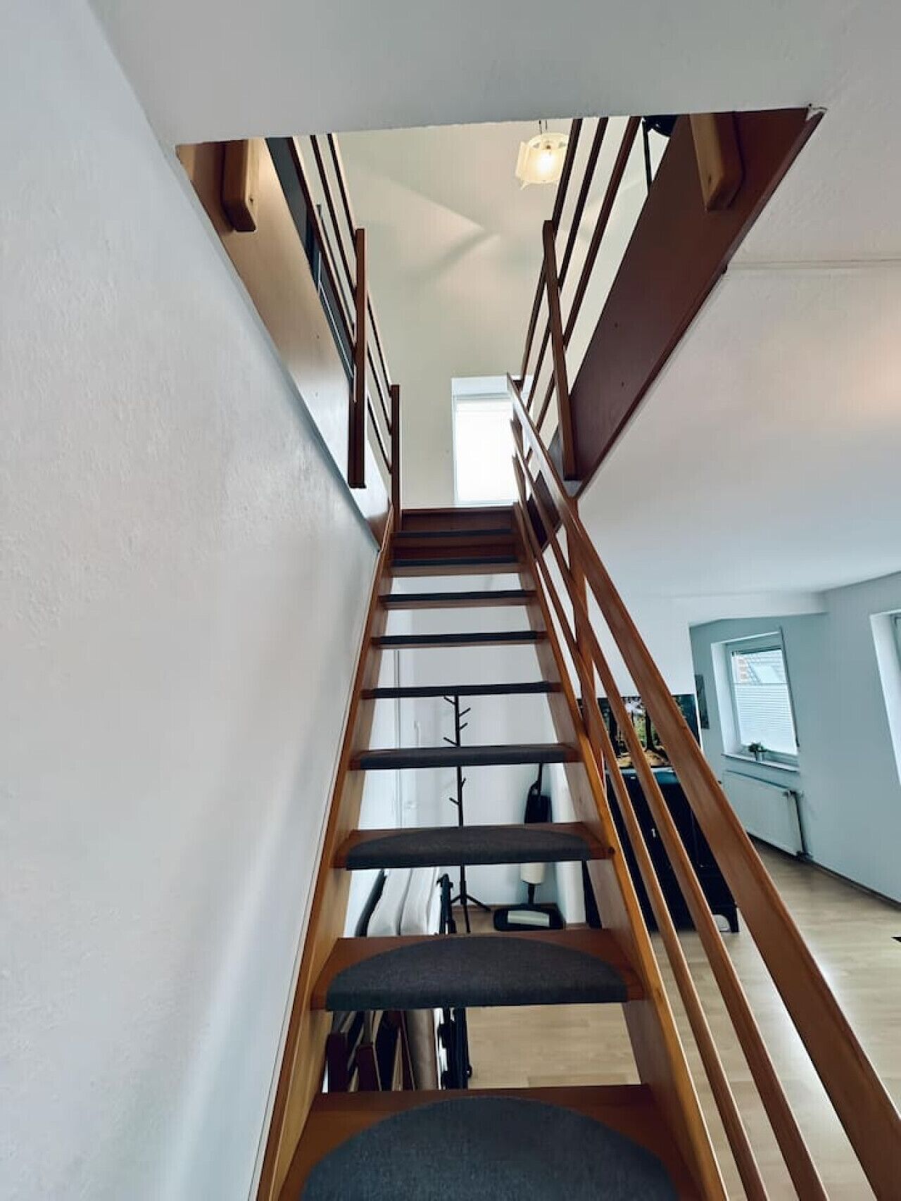 Un escalier en bois, doté d’une rampe, menant à l’étage supérieur.