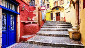 A narrow street with a red door and a blue door, leading to a set of stone steps.