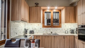 A modern kitchen with wooden cabinets, a countertop with a speckled backsplash, and a window with a metal railing.
