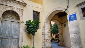 A narrow street with a stone archway, a wooden door, and a sign indicating a business.