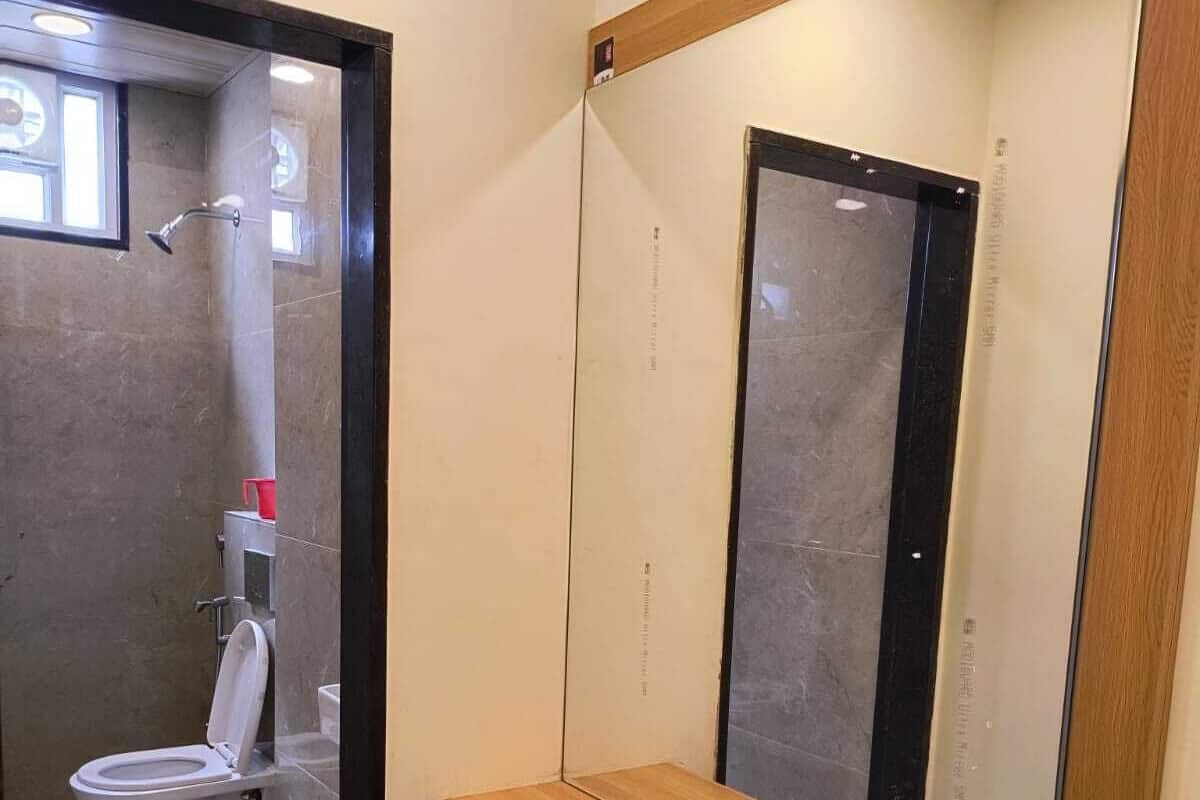A bathroom with a wooden vanity, a mirror, and a toilet.