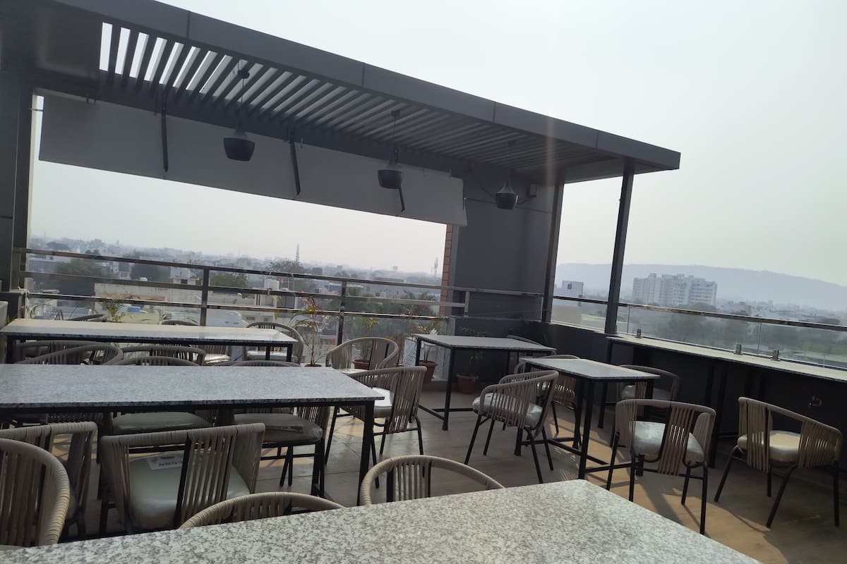An outdoor seating area with tables and chairs, overlooking a cityscape.
