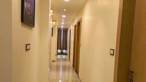 A hallway with a polished floor, recessed lighting, and wooden doors. - Hotel Mewar Shine (Udaipur)