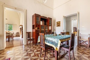 A dining area with a table set for four, surrounded by wooden chairs. A large wooden cabinet with glass doors is positioned behind the table. The room has a tiled floor with a geometric pattern. - 3728 Villa Donna Linda by Barbarhouse (Taviano)