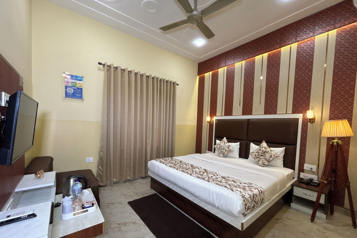 A hotel room with a bed, desk, chair, curtains, and a ceiling fan.