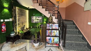 A staircase with a Buddha statue, a neon sign, magazines, and a fire extinguisher. - The Orchid Retreat Agra - Stay Near Taj Mahal (Agra)
