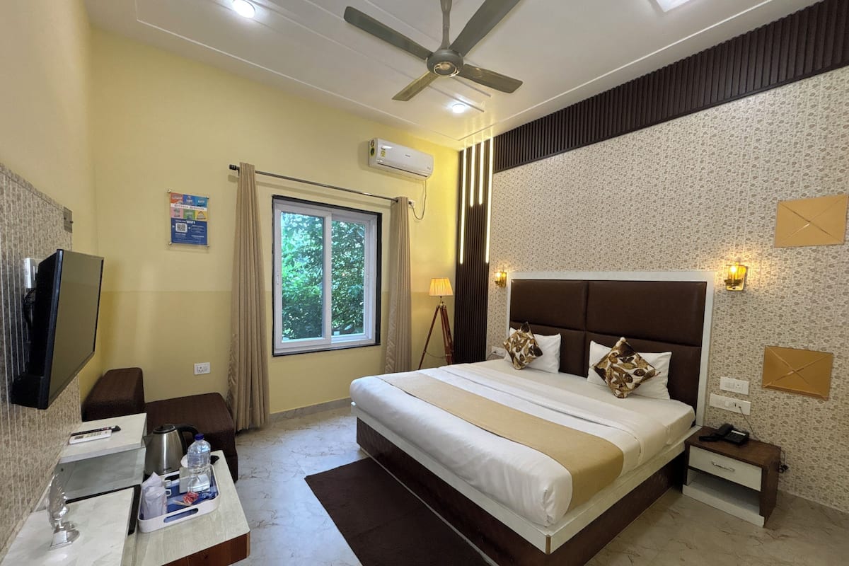 A hotel room with a bed, bedside table, TV, and a window with curtains.