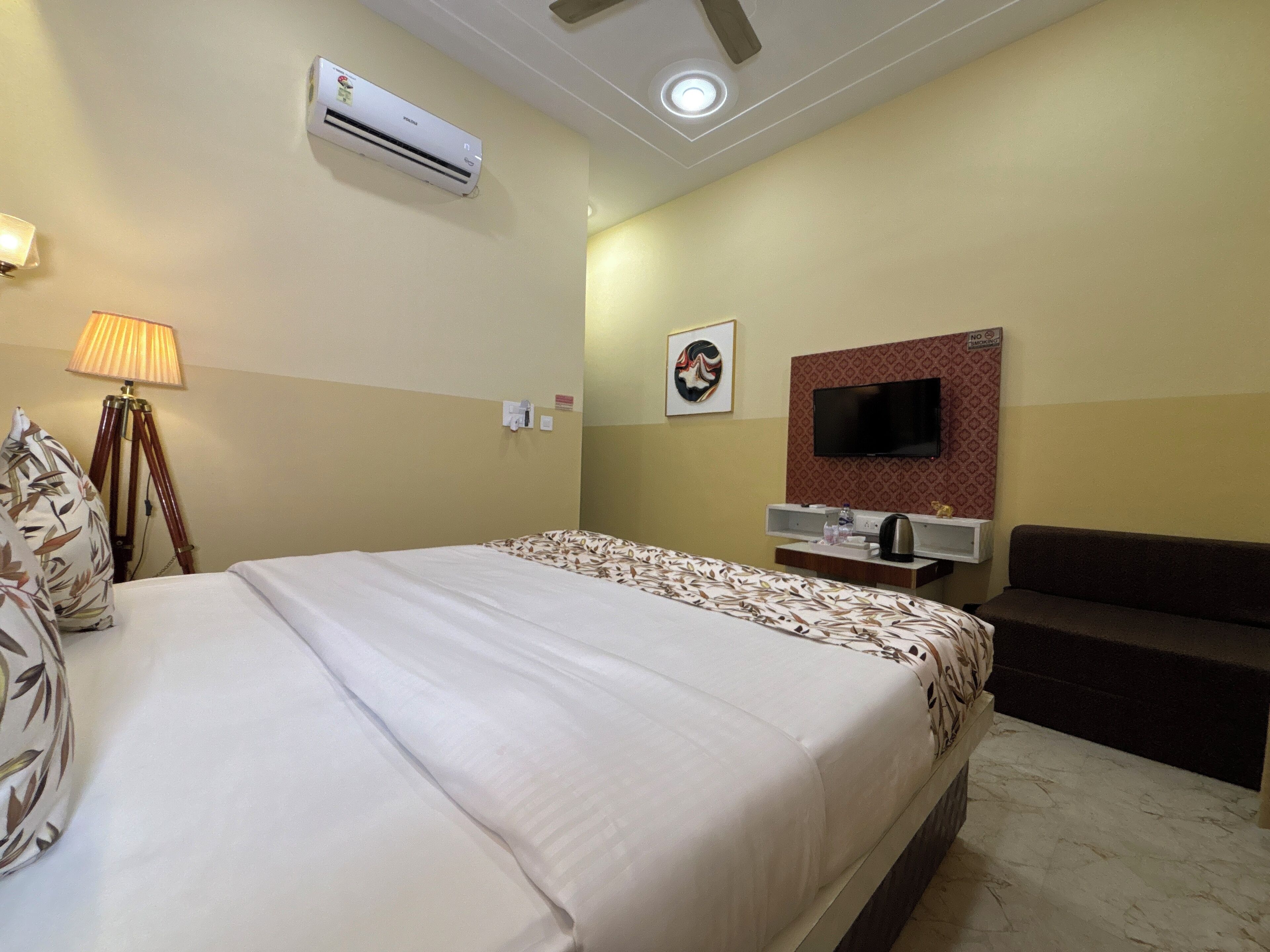 A hotel room with a bed, a TV, a desk, and a sofa.