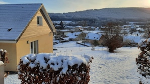A snow-covered residential area with houses and a hill in the background.