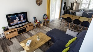 A modern living room with a television, sofa, coffee table, and dining area.