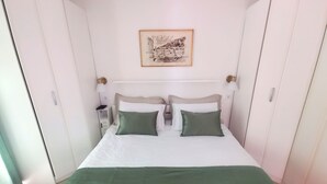 A neatly made bed with two pillows, a bedside table with a lamp, and a framed picture on the wall. - Mario` place - penthouse with sea view terrace (Dubrovnik)