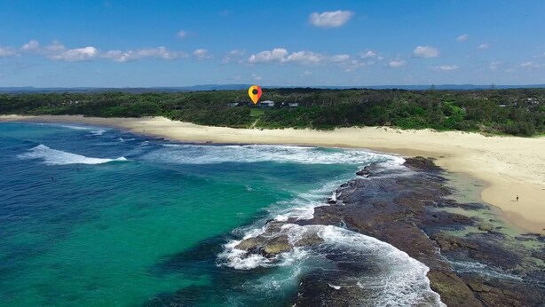 A coastal beach with clear turquoise waters, rocky shoreline, and a sandy beach. - Beachside Cottage - Cudmirrah (Cudmirrah)