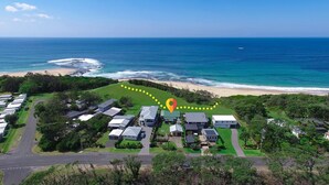 An aerial view of a coastal residential area with houses, a beach, and the ocean. - Beachside Cottage - Cudmirrah (Cudmirrah)