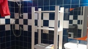 A bathroom with a checkered blue and white tile wall, a white sink, and a shower area. - Haut DE Villa Equipee, Tout Confort, Style Loft (Lamentin)