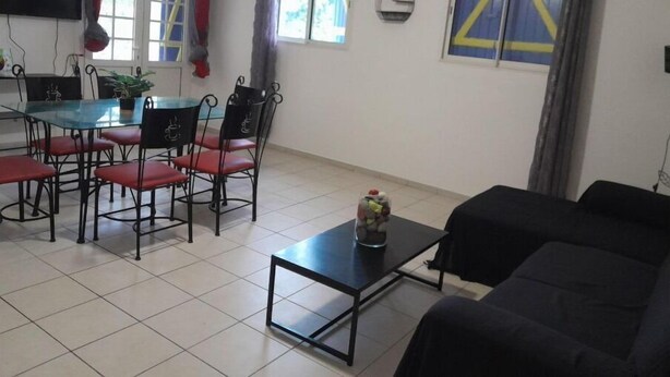 A living room with a glass dining table, red chairs, a black sofa, and a small coffee table. - Haut DE Villa Equipee, Tout Confort, Style Loft (Lamentin)