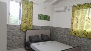 A single bed with a grey headboard and white bedding in a room with a tiled floor and a grey and white patterned wall. - Haut DE Villa Equipee, Tout Confort, Style Loft (Lamentin)