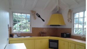 A kitchen with yellow cabinets, a white countertop, a black microwave, and a window with a view of greenery. - Haut DE Villa Equipee, Tout Confort, Style Loft (Lamentin)