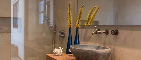 Une salle de bain moderne avec une douche à parois de verre, un meuble-lavabo en bois et des éléments décoratifs tels qu’un lavabo en forme de bol et des étoiles de mer.