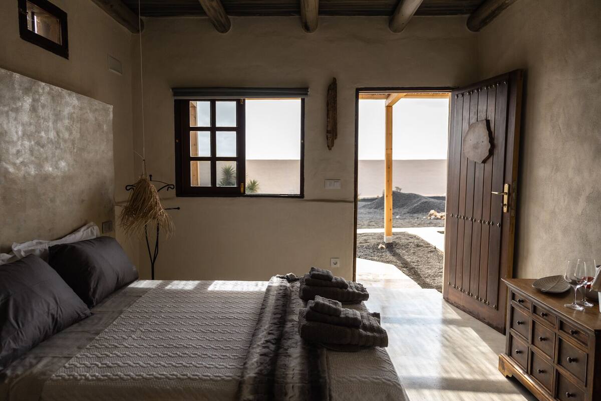 Un dormitorio con cama, ventana, puerta y cómoda.