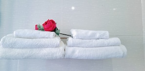 A stack of white towels and a single red rose on a white surface. - Blue Fish Villa (Da Nang)