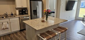 A kitchen with a granite countertop, stainless steel appliances, a coffee maker, and a vase with flowers. - Near Bethany: Fenced Yard, Game Room, Pools, Dogs (Millville)