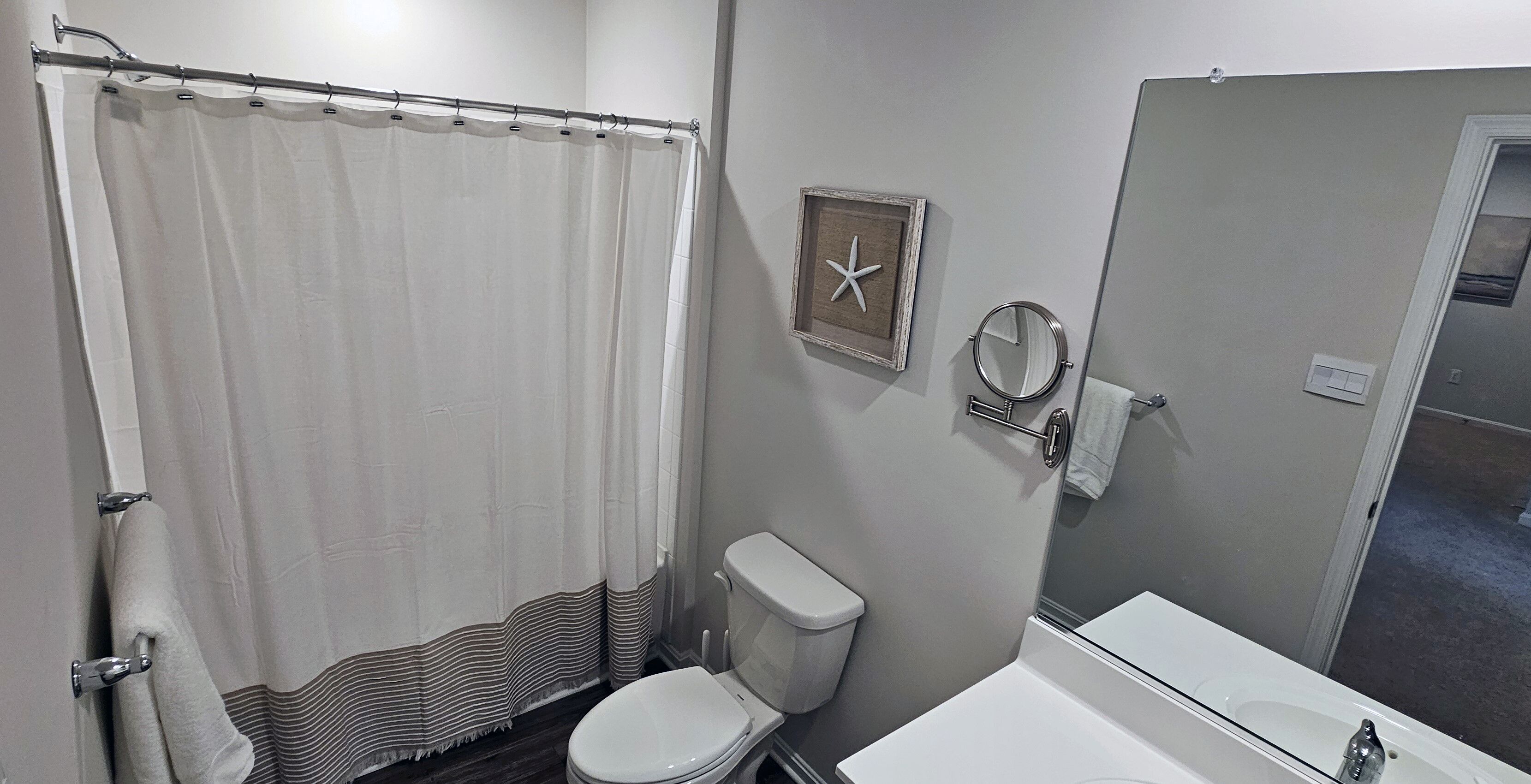 Une salle de bain avec un rideau de douche, des toilettes et un miroir.