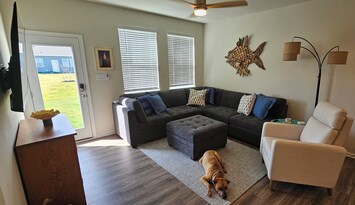 Family Room with large sectional & ottoman.
65" Smart TV, Open concept for families.