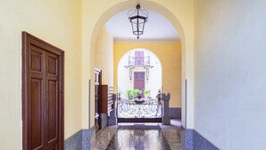A hallway with a marble floor, a wooden door, and a wrought iron gate leading to a balcony with plants. - Easylife - Prestigious apartment in Risorgimento (Milano)