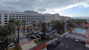 Ein Hotel mit einem großen Gebäude mit der Aufschrift „Columbus“ und einem Parkplatz mit mehreren Autos und Palmen.
