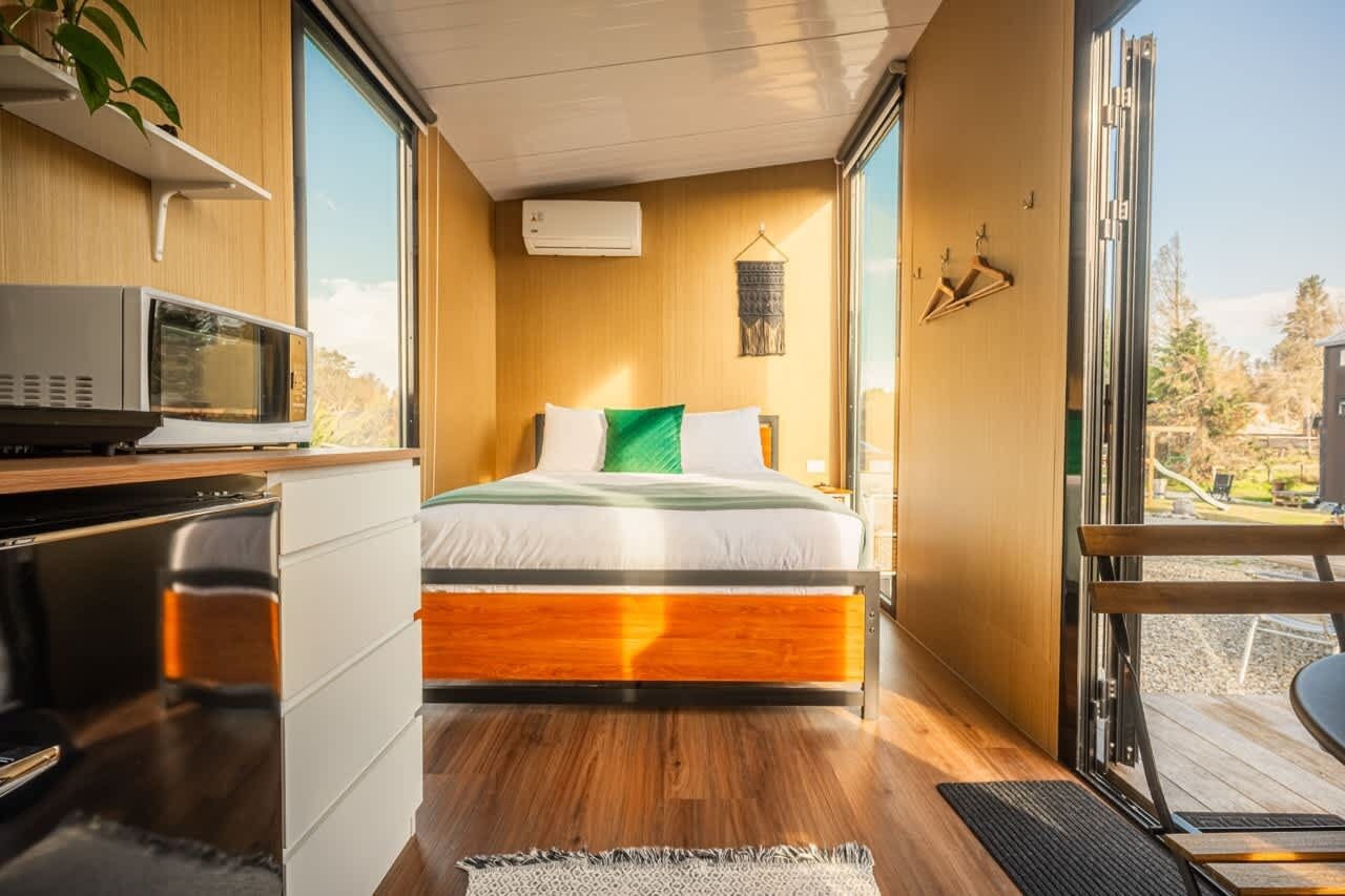 A compact bedroom with a bed, a microwave, and a small kitchenette.