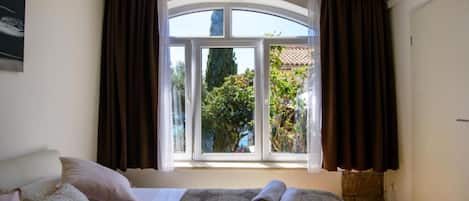 Habitación de hotel con una cama grande, una ventana con cortinas y vistas a zonas verdes.