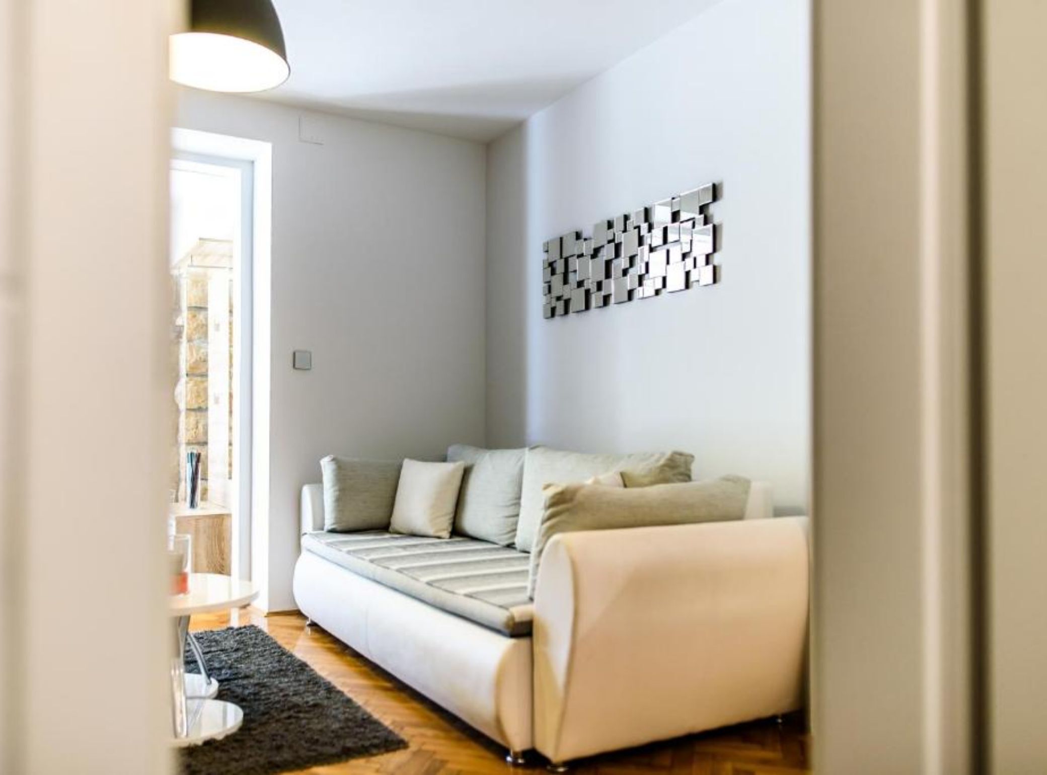 A modern living room with a sofa, a decorative wall piece, and a small table.