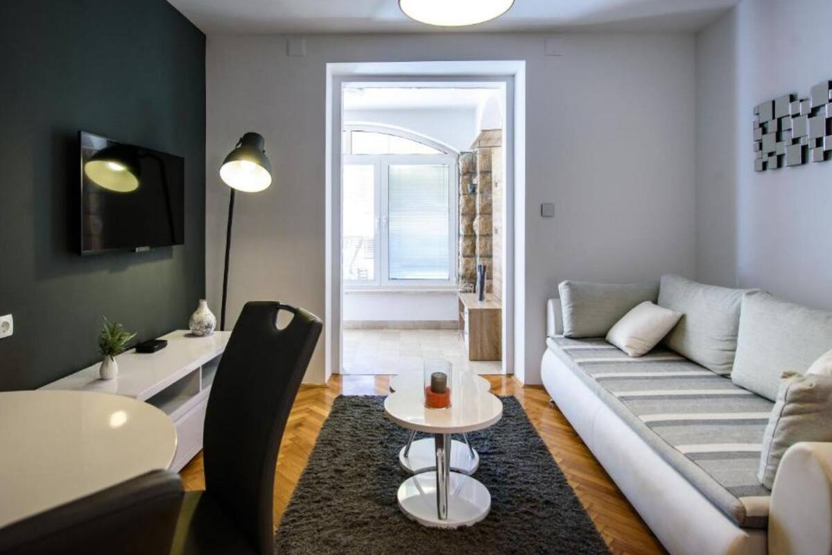 Ein modernes Wohnzimmer mit Sofa, Fernseher, Lampe und Essbereich.