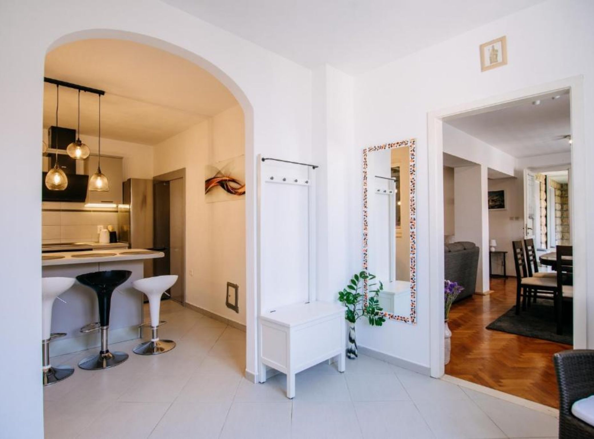 A modern kitchen with a bar area, white cabinetry, and pendant lighting.