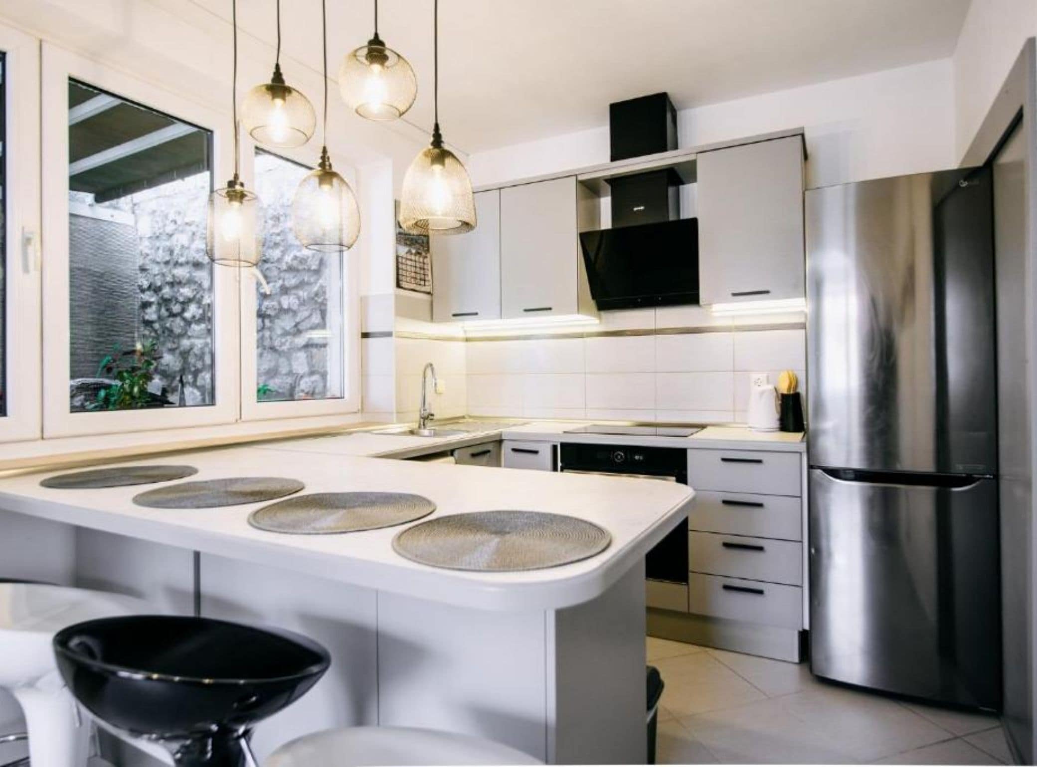 A modern kitchen with a central island, stainless steel appliances, and pendant lighting.