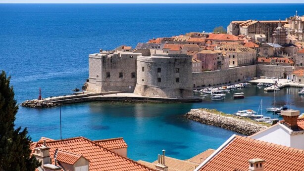 A coastal city with a historic fortification, a harbor with boats, and traditional red-tiled rooftops. - Apartments Luce & Toma (Dubrovnik)
