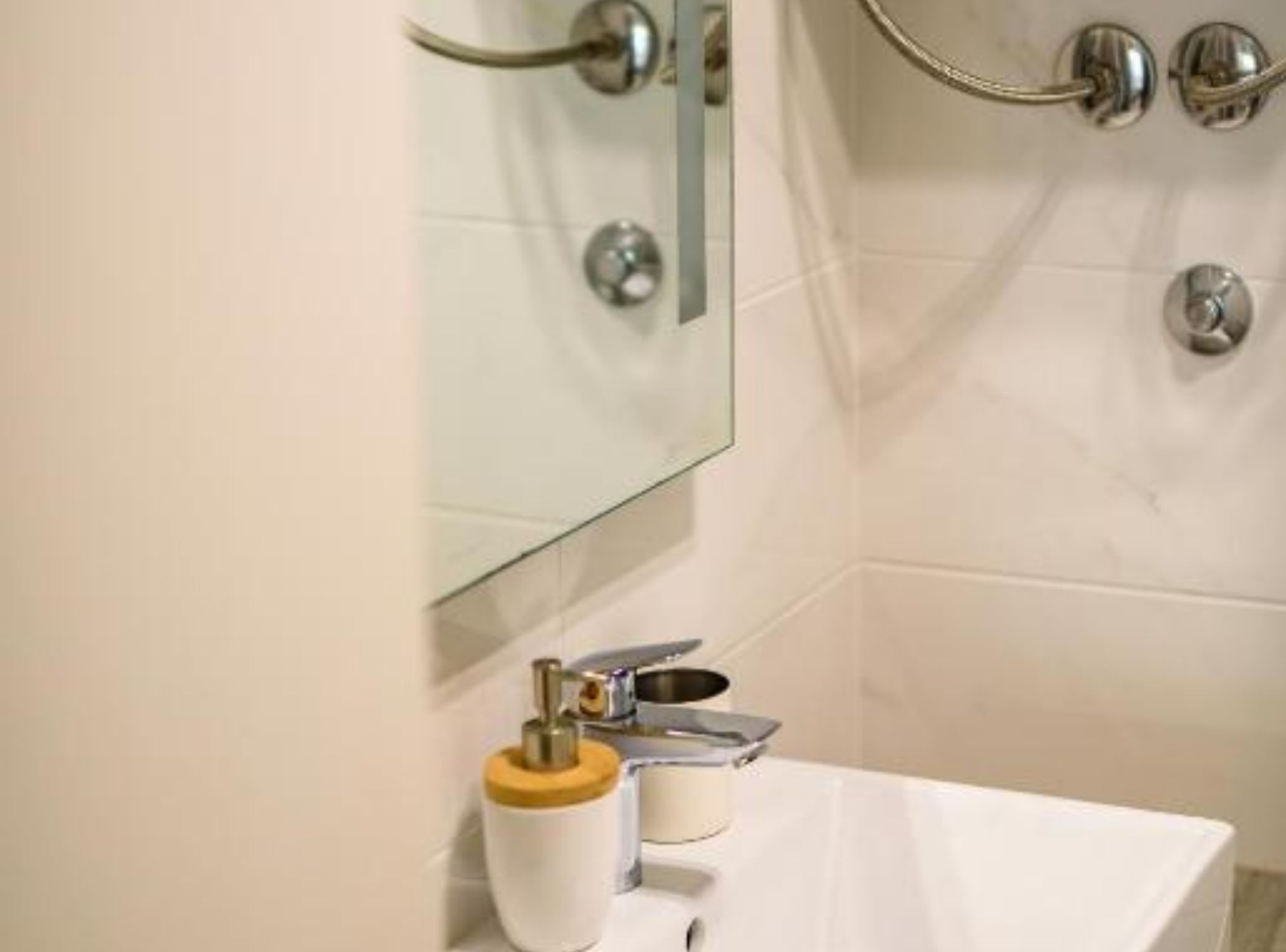 A bathroom with a white sink, a mirror, and a shower area with a glass door.
