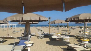 Une plage avec de nombreux parasols et des chaises longues.